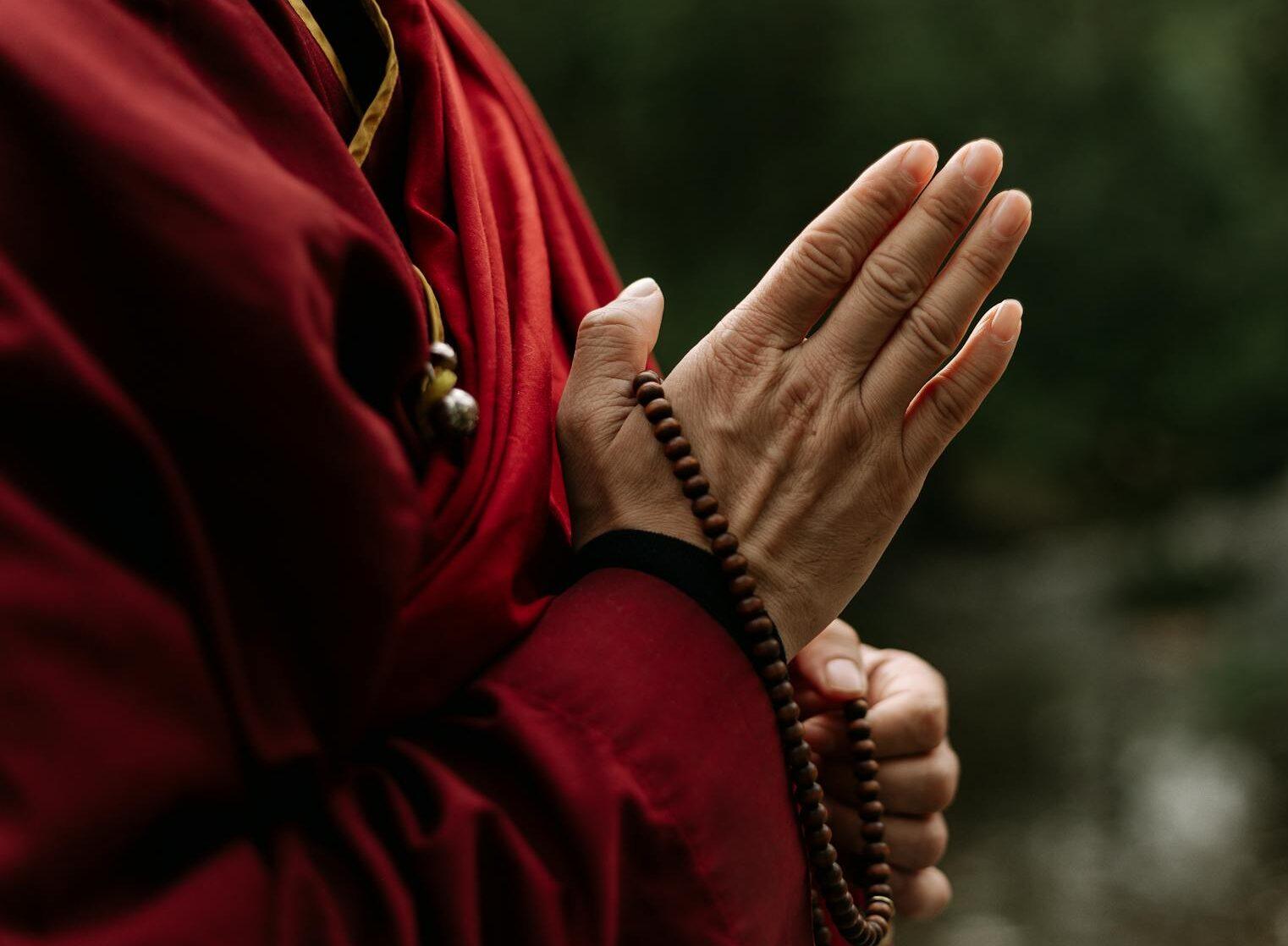 hands holding a brown prayer beads