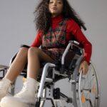 a low angle shot of a woman in red long sleeves sitting on the wheelchair