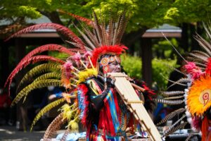 man in traditional native american clothing playing music on festival